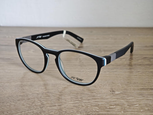 May include: Black eyeglasses with oval frames and a thin white and light blue trim. The temples are black with a gray and white accent. The brand name "JF Rey" is visible on the lens. The glasses are on a wooden surface.